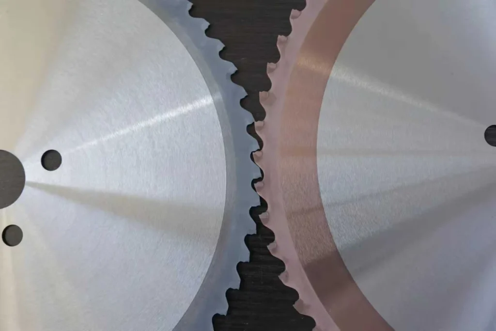 Close-up of two saw blade tooth profiles showing different coating colours
